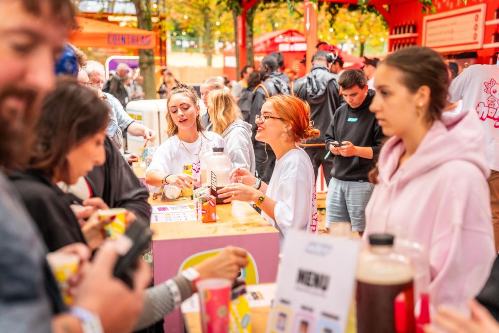Hôtesses en tee-shirt Holy servant la dégustation gratuite au comptoir, gobelets et menu des boissons au premier plan