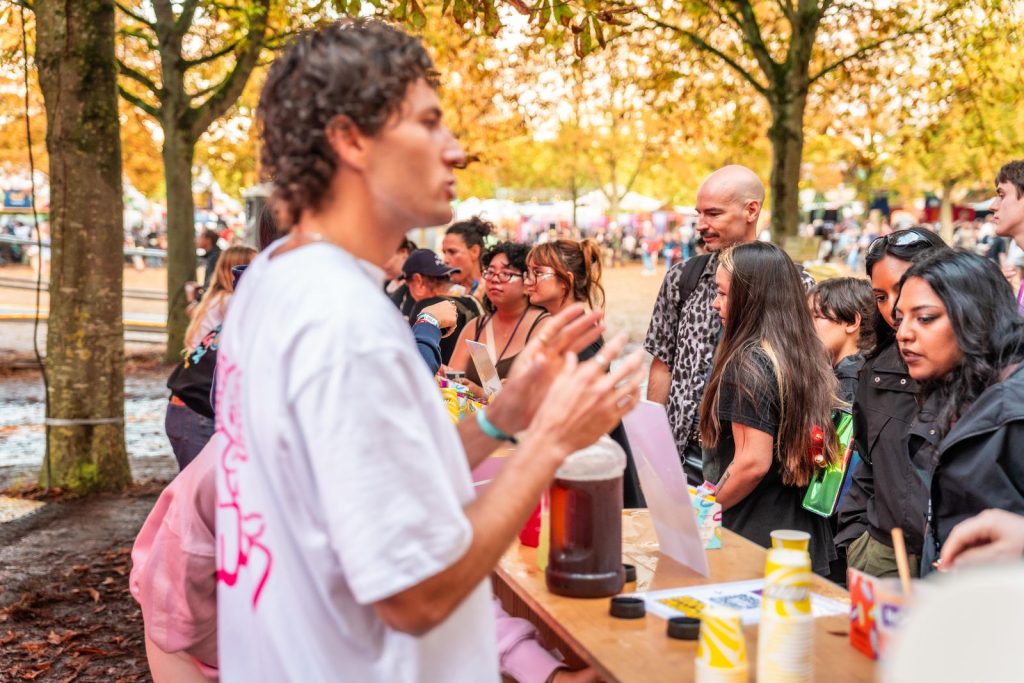 Un animateur Holy présente les boissons à des festivaliers devant le comptoir de dégustation, à Rock en Seine