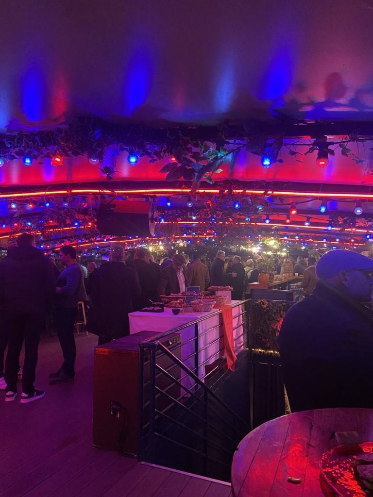 Invités de la soirée post-salon Hanwha réunis autour du buffet à bord de la péniche River’s King, sous des guirlandes lumineuses rouges et bleues