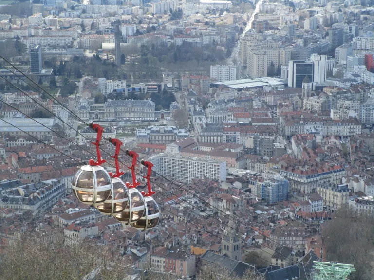Les cabines rouges du téléphérique de la Bastille au-dessus des toits de Grenoble