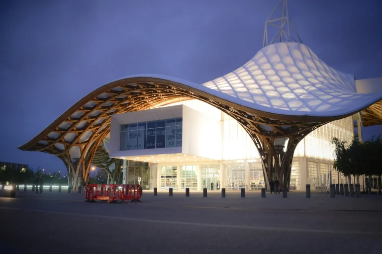 Le Centre Pompidou-Metz et sa grande toiture ondulée en bois et toile blanche, éclairé à la tombée de la nuit