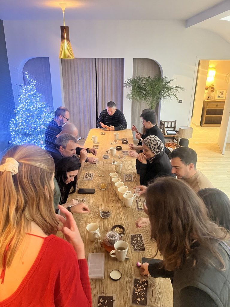 Participants qui décorent des tablettes de chocolat autour d’une longue table, à côté d’un sapin illuminé, pendant la journée d’étude de décembre d’Insight