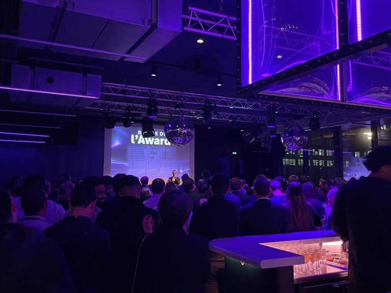 Remise des prix de l’Awards Dinner de Scalian au Nodd, à La Défense : un intervenant au micro devant l’écran, invités debout vus de dos