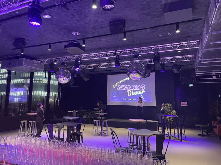 La sala del Nodd antes de la llegada de los invitados: una pantalla con el texto «Bienvenue Awards Dinner Scalian», bolas de espejos y mesas altas, en La Défense