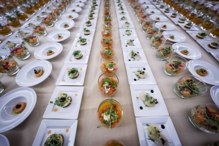 Entrées et verrines dressées en longues rangées sur une table nappée, pendant la convention du Groupe Positive à Bruxelles