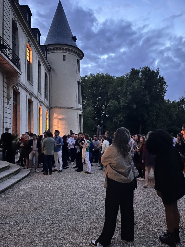 Apéritif à la tombée du jour dans la cour du Château d’Ermenonville, participants réunis au pied de la tour éclairée