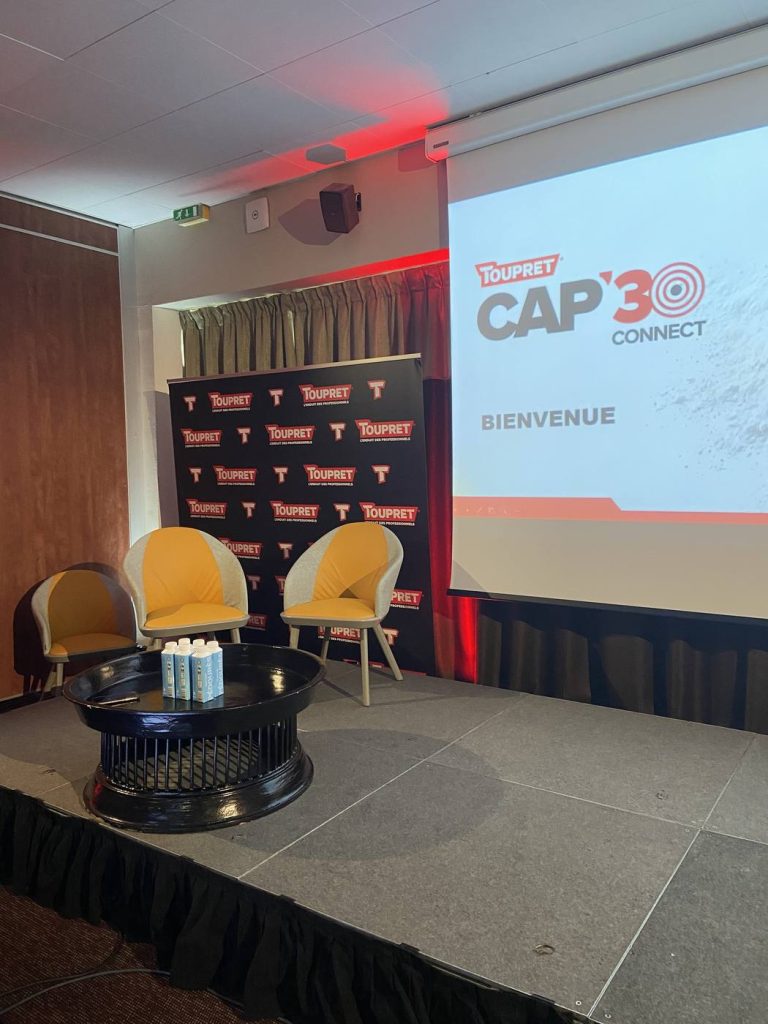 Scène de la convention hybride Cap 30 Connect de Toupret au Residhome Suites Sénart : fauteuils, mur de logos et grand écran de bienvenue