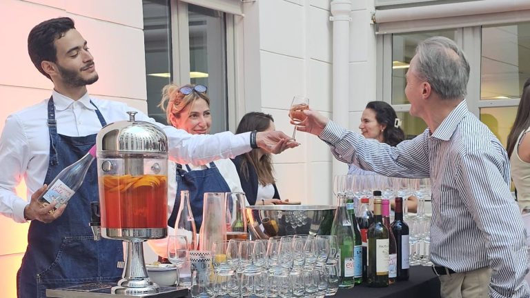 Barman servant un cocktail de fruits à un invité, au bar dressé dans la cour des bureaux de Coty pour sa soirée d’été
