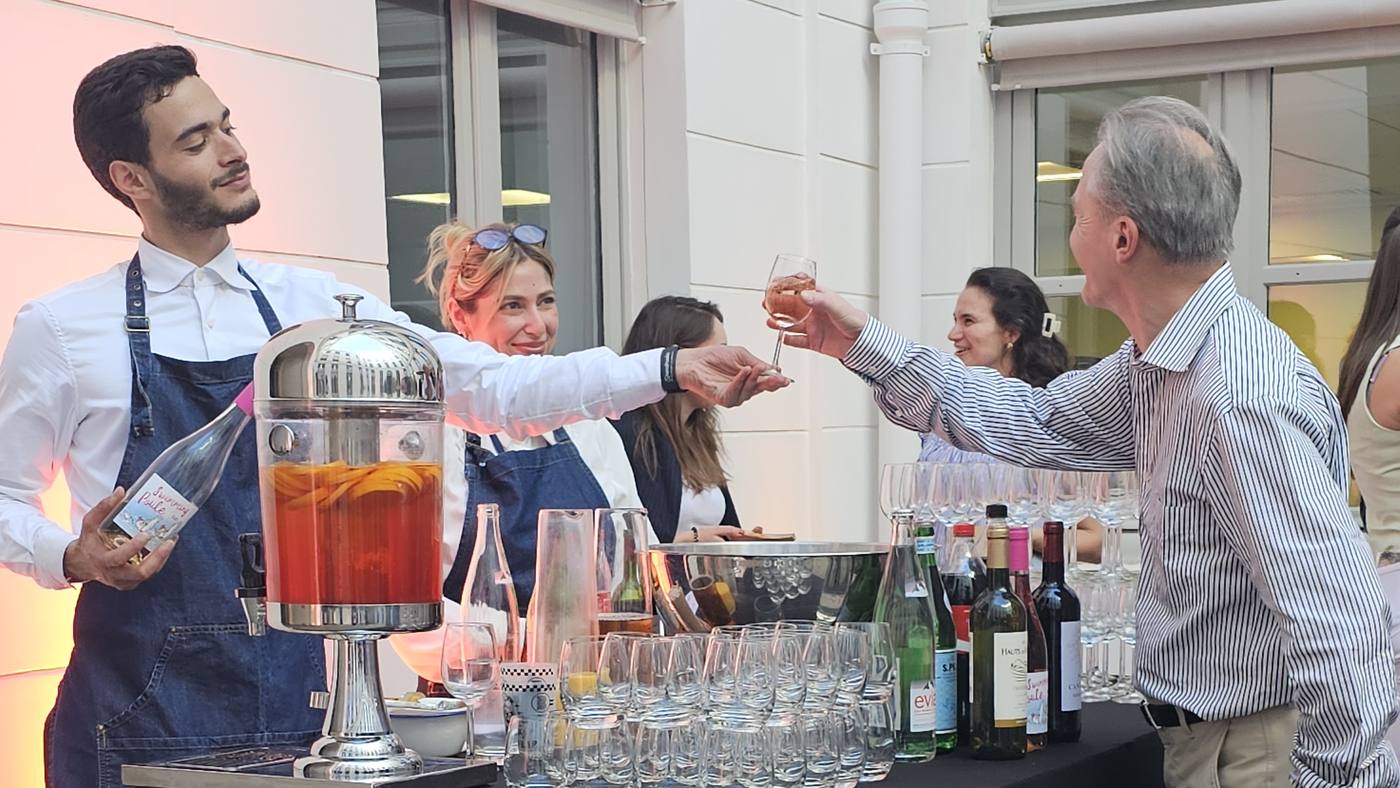 Barman servant un cocktail de fruits à un invité, au bar dressé dans la cour des bureaux de Coty pour sa summer party