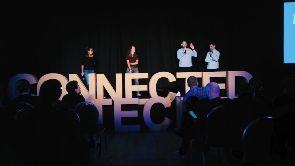 Cuatro ponentes en el escenario tras las grandes letras «Connected Tech», frente al público de la sesión plenaria del seminario de KPMG