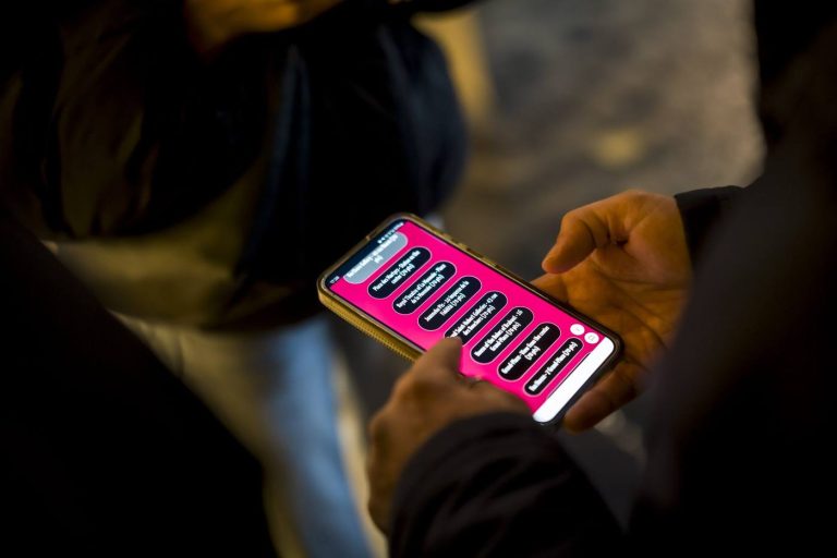 Gros plan sur le téléphone d’un participant affichant une liste de choix sur fond rose, pendant la convention du Groupe Positive organisée par Weevup à Bruxelles