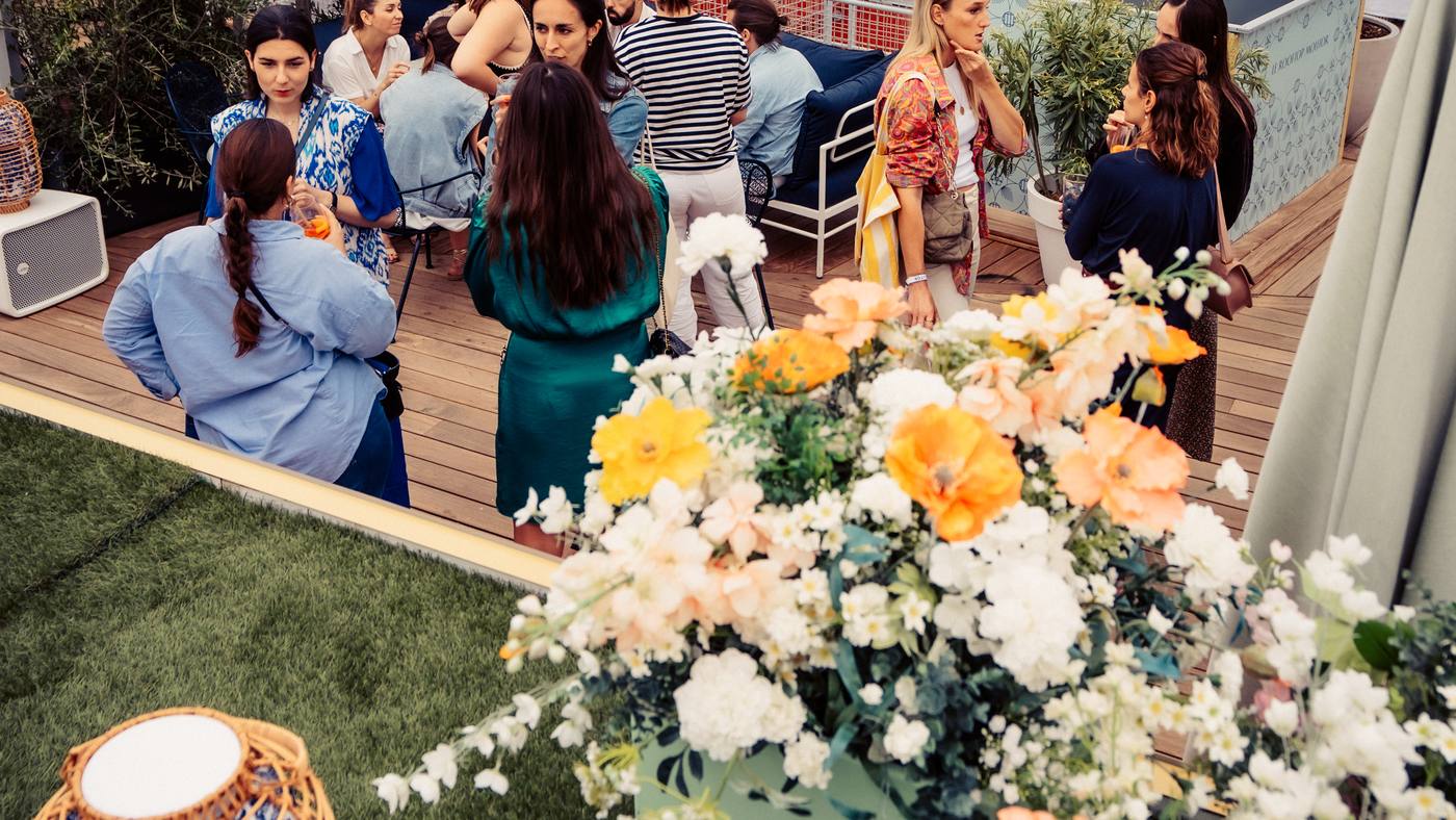 Invités réunis sur le rooftop de la cocktail party Dior organisée par Weevup, entre compositions de fleurs et lanterne en rotin