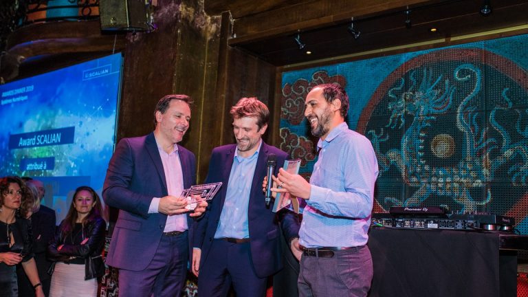 Remise d’un award sur scène pendant la soirée de remise de prix de Scalian, devant un écran annonçant l’Award Scalian
