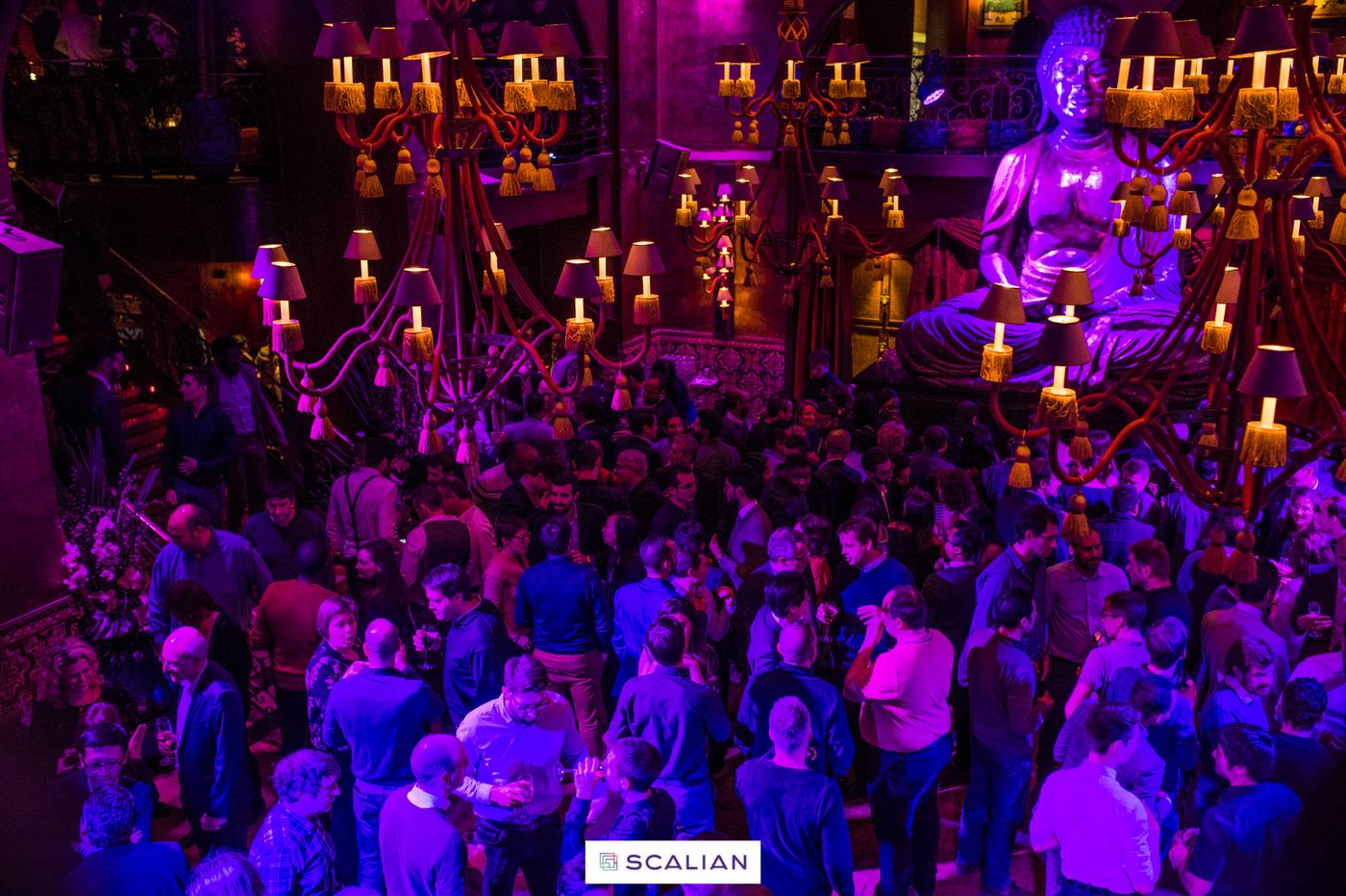 Collaborateurs de Scalian réunis sous des lustres à bougies et un éclairage violet, lors d'une soirée organisée par Weevup