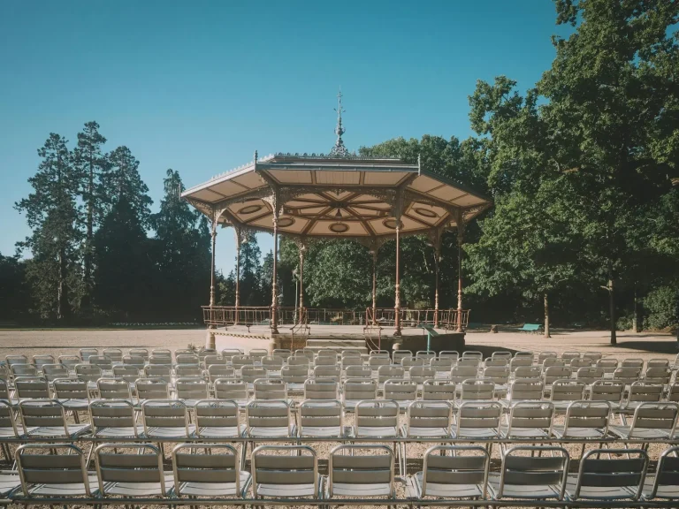 Le kiosque à musique du parc du Thabor, à Rennes, face à des rangées de chaises, entouré de grands arbres