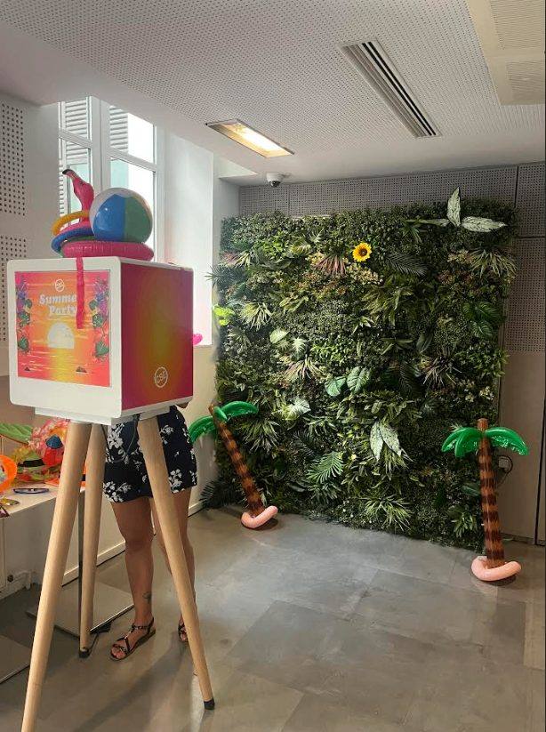 Photobooth installé devant un mur végétal entouré de palmiers gonflables, pour la Summer Party de Coty organisée par Weevup dans ses bureaux