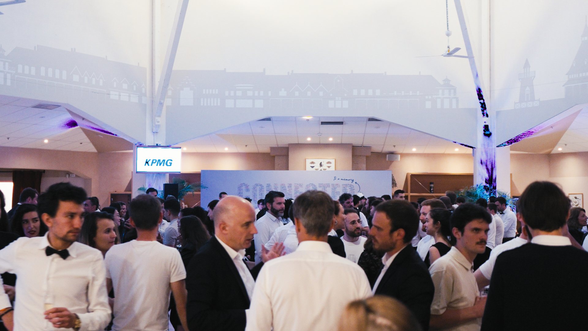 Collaborateurs de KPMG réunis et échangeant en tenue de soirée sous une grande structure lumineuse, pendant le séminaire organisé par Weevup