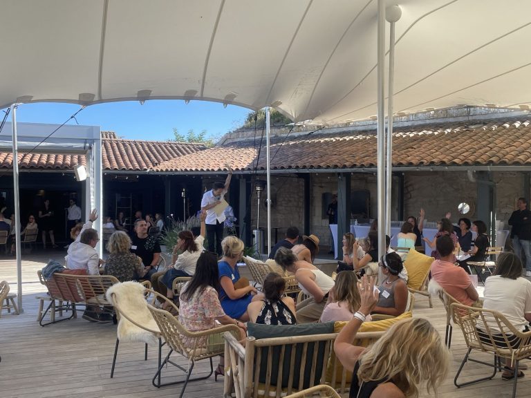 Un animateur s’adresse aux collaborateurs d’Excelia, dont plusieurs lèvent la main, sous la tente du Bastion, à Saint-Martin-de-Ré, sur l’île de Ré
