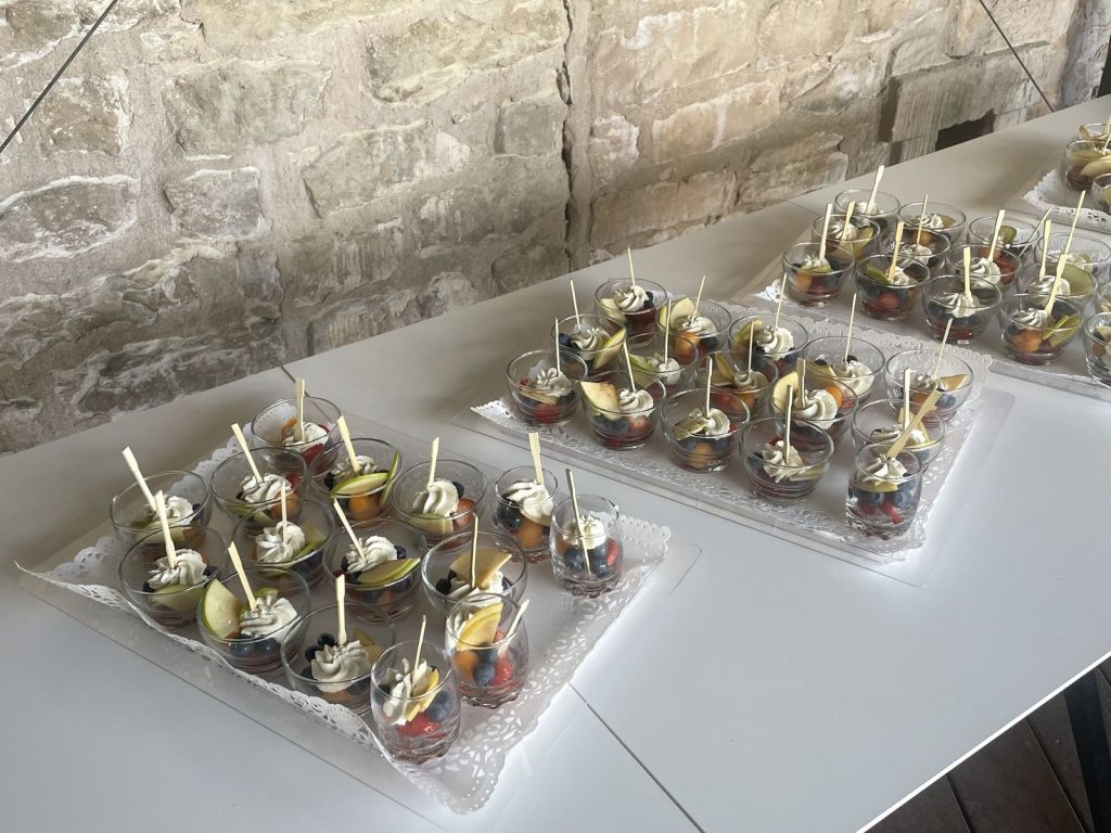 Verrines de fruits frais servies à l’accueil de l’après-midi, sur un buffet blanc devant un mur de pierre du Bastion, à Saint-Martin-de-Ré