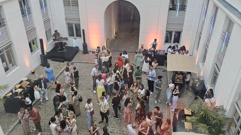 Vue plongeante sur la soirée d’été de Coty dans la cour pavée de ses bureaux : invités, DJ, bar et stands de restauration