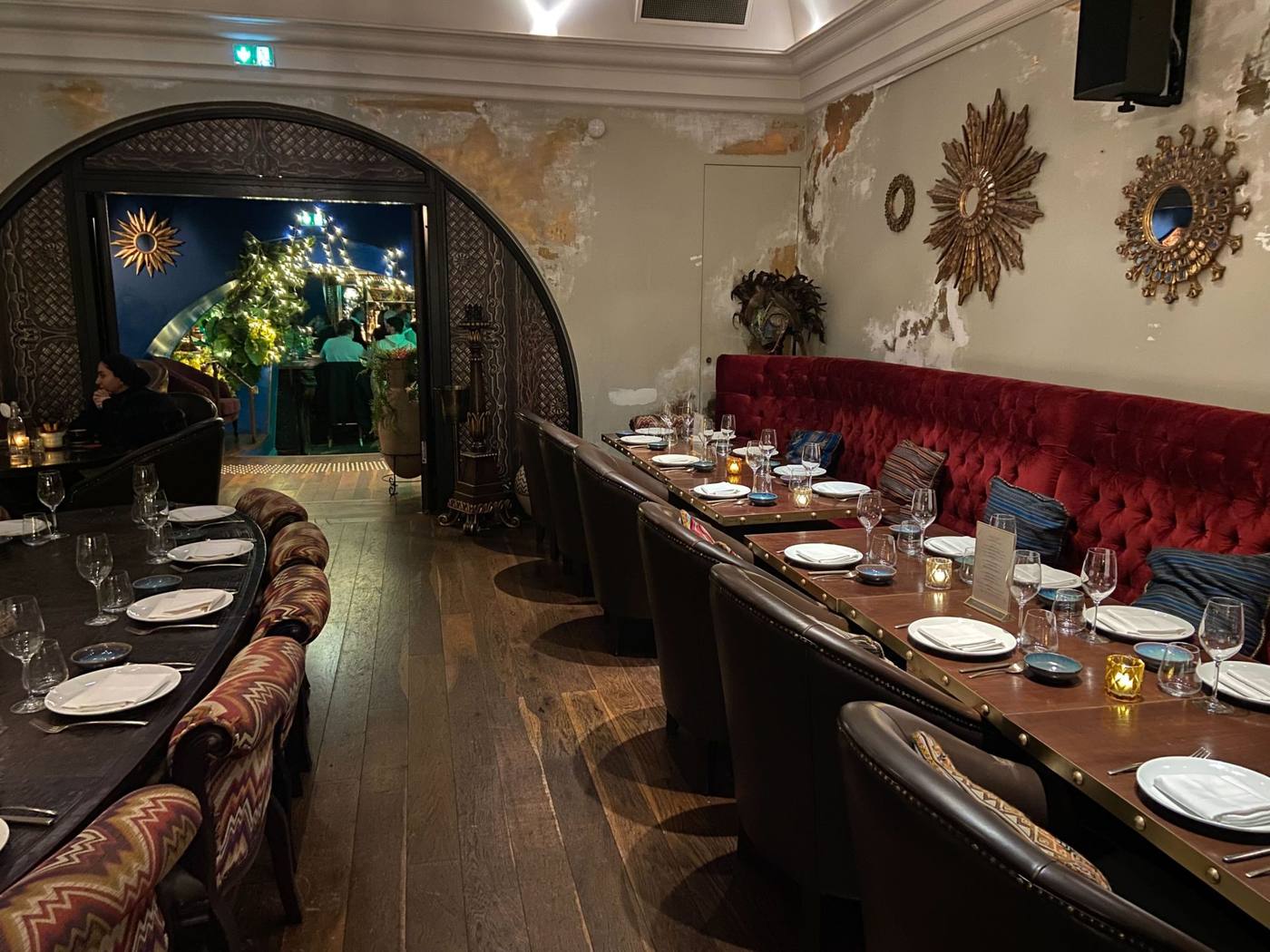 Salle de restaurant aux banquettes de velours rouge et aux miroirs soleil dorés, tables dressées pour la soirée de Norman K organisée par Weevup