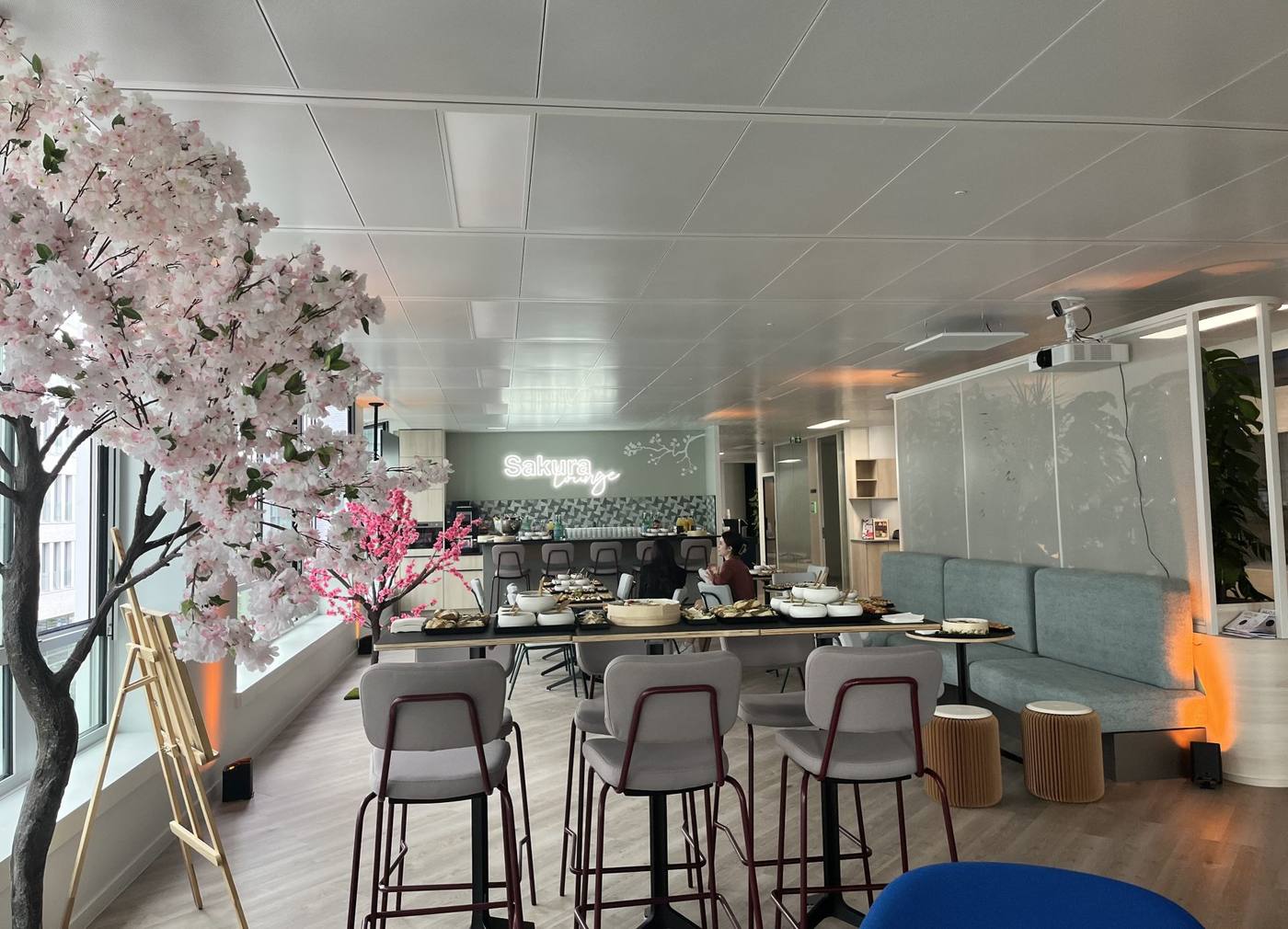 Espace cocktail « Sakura Lounge » des nouveaux locaux de Daiichi, décoré de cerisiers en fleurs, avec buffet et tables hautes, lors de l'inauguration organisée par Weevup