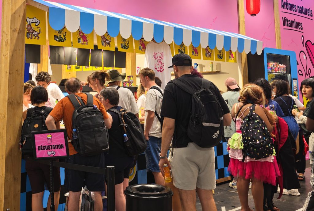 Festivaliers dégustant les boissons Holy au comptoir de dégustation du stand, à Japan Expo