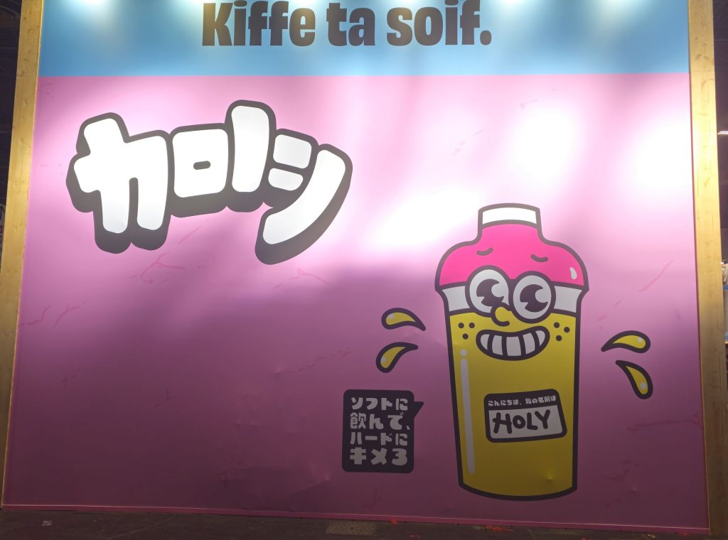 Mur de marque Holy « Kiffe ta soif. » avec la mascotte shaker et un lettrage japonais sur fond rose