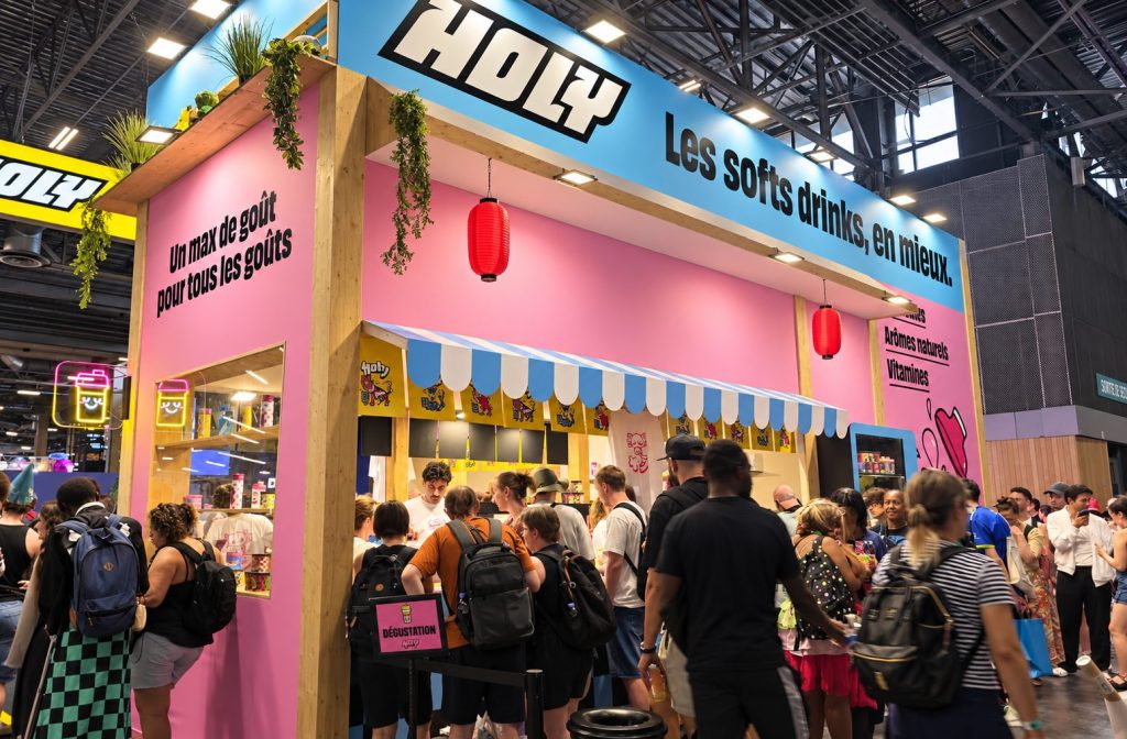 Stand Holy à la Japan Expo : enseigne « Les softs drinks, en mieux. », lanternes rouges et file de visiteurs au comptoir