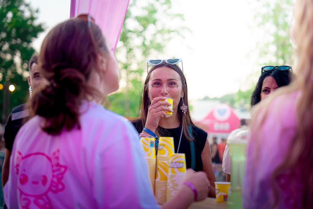 Festivalière goûtant une boisson Holy au comptoir de dégustation, face à une hôtesse, au Lovely Brive Festival