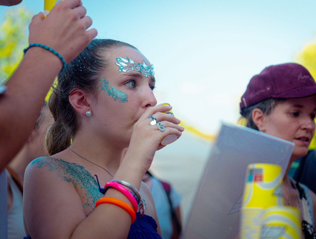 Festivalière pailletée buvant une boisson Holy en gobelet devant le bar de dégustation du Lovely Brive Festival