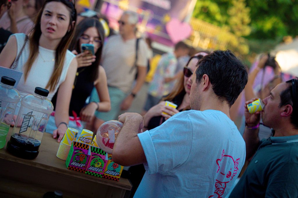 Hôte servant les boissons Holy au comptoir pendant que des festivaliers dégustent, au Lovely Brive Festival