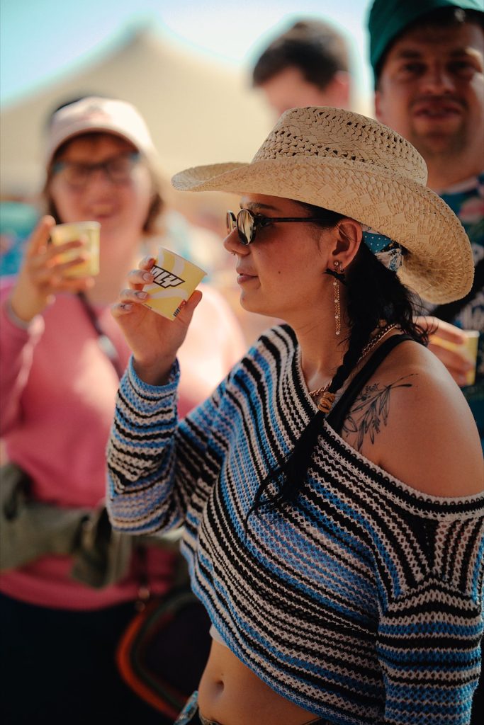 Festivalière au chapeau de paille goûtant une boisson Holy, au Marvellous Island Festival