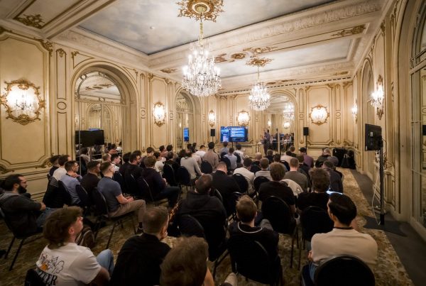 Plénière de la convention de janvier du Groupe Positive à Bruxelles, organisée par Weevup : participants assis face aux écrans dans un salon aux moulures dorées, sous des lustres en cristal