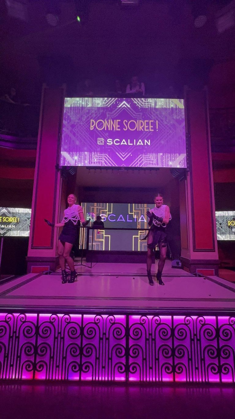 Deux danseuses en robe noire sur une scène éclairée de violet, sous un écran aux motifs Art déco affichant « Bonne soirée ! » et le logo Scalian, pendant la soirée awards années folles organisée par Weevup