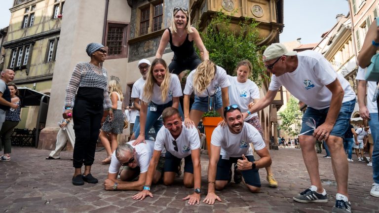 Elanco staff in white T-shirts forming a human pyramid on a cobbled street in Colmar, during the digital rally of their retreat