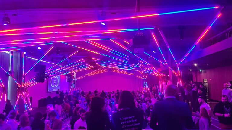 Collaborateurs de 3DS Outscale réunis sous une structure de néons roses et bleus, pendant la convention annuelle organisée par Weevup à Paris