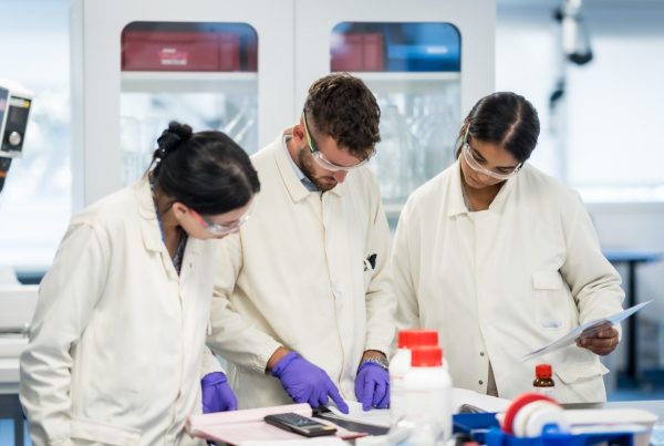 Collaborateurs en blouse blanche, lunettes et gants de protection, penchés sur un plan de travail dans un laboratoire du site de production d'Elanco, pendant le séminaire annuel organisé par Weevup