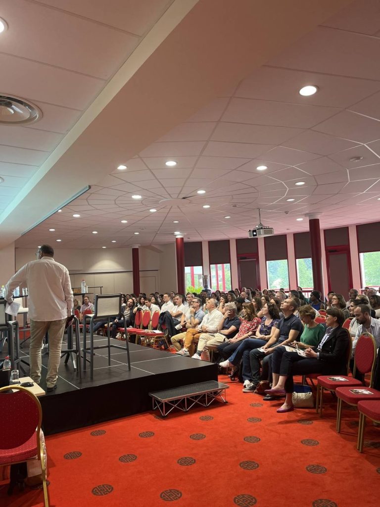 Intervenant sur une petite scène face aux participants assis en rangs, dans la salle plénière du séminaire d’un groupe bancaire organisé par Weevup au Zoo de Beauval