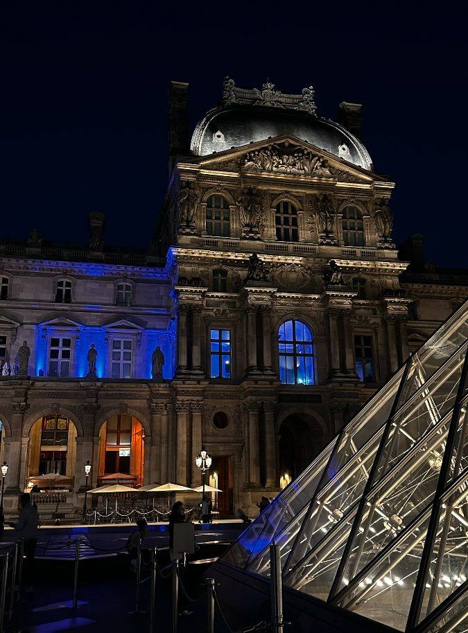 Façade du Louvre éclairée de bleu et pyramide de verre de nuit, lieu du dîner Iron Mountain organisé par Weevup