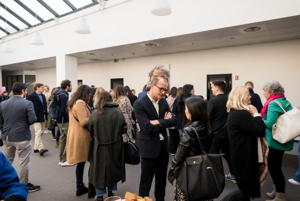 Participants du séminaire international SVR organisé par Weevup, manteaux sur le dos et sacs à l'épaule, réunis sous la verrière d'un atrium autour d'un café d'accueil
