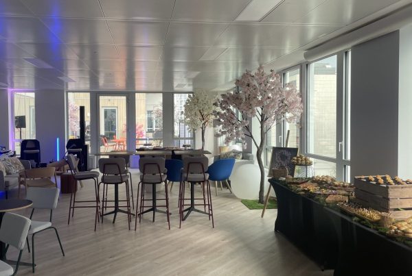 Salle des nouveaux locaux de Daiichi préparée pour l'inauguration organisée par Weevup : cerisiers en fleurs, tables hautes et buffet de pièces cocktail le long des baies vitrées