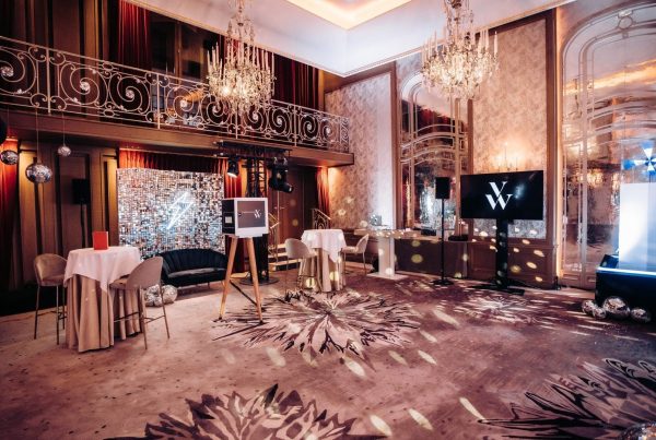 Salon à lustres aménagé par Weevup en plusieurs espaces : mange-debout nappés, mur de sequins, écran au logo de la marque et socle de présentation éclairé, pour la soirée de lancement de Vanessa Wu