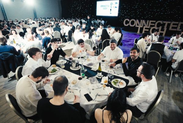 Collaborateurs attablés autour de tables rondes nappées de blanc pendant le dîner de gala du séminaire KPMG organisé par Weevup, devant de grandes lettres « Connected Tech »