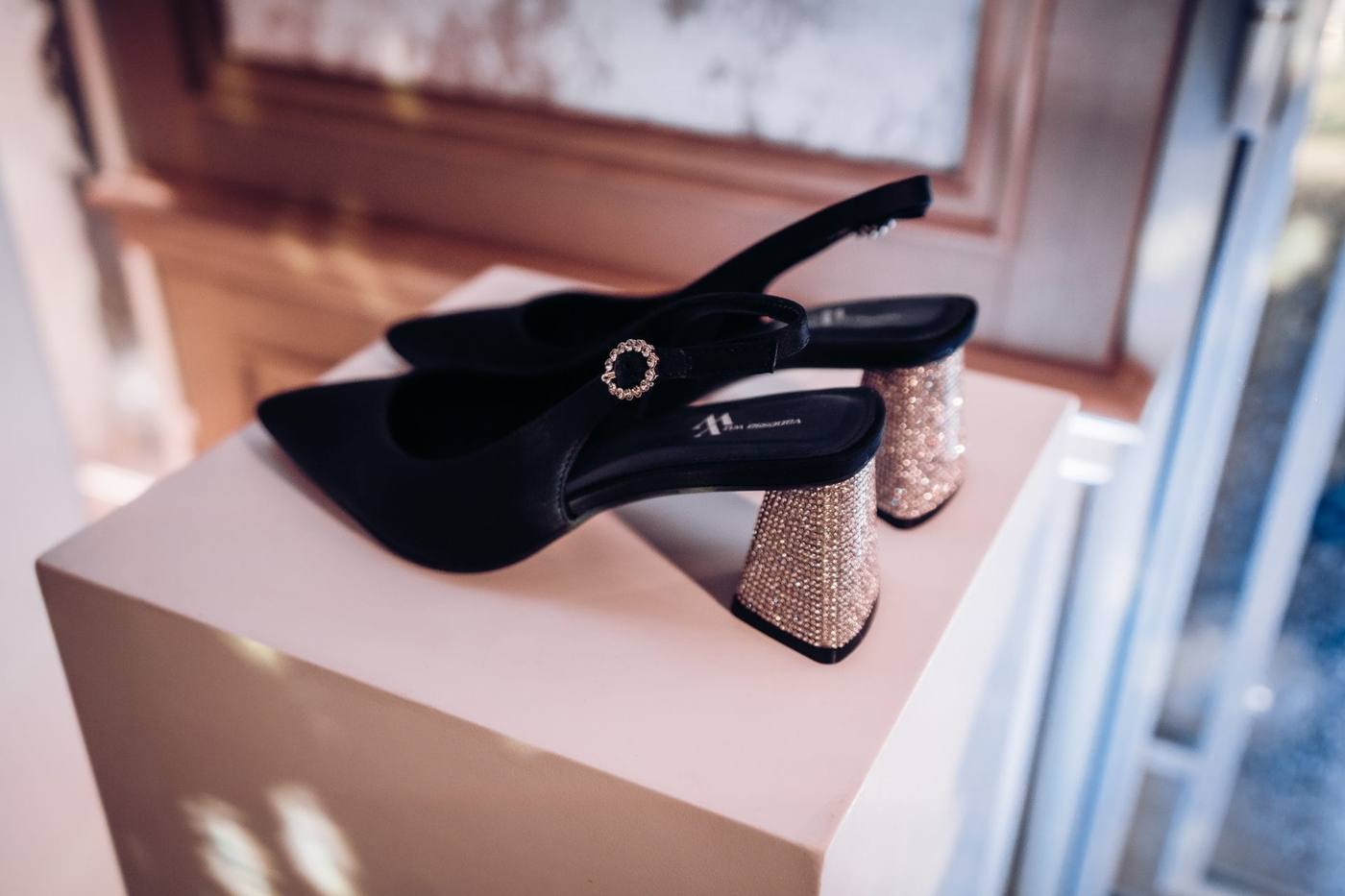 Escarpin noir à talon scintillant présenté sur un socle blanc, lors de la soirée de lancement de produit de Vanessa Wu organisée par Weevup