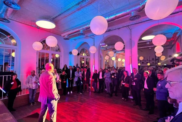 Prise de parole devant les invités de la soirée de lancement de marque de Groupe Atlantic, sous un éclairage rose et bleu et des suspensions en forme de globes