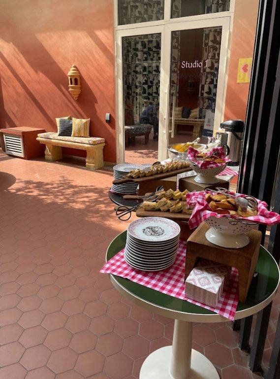 Buffet de viennoiseries servi au soleil sur une table nappée de vichy rouge, pendant une pause du roadshow de Parthena