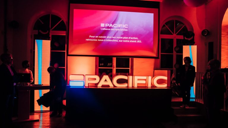 Scène de la soirée de lancement de marque de Groupe Atlantic : lettres lumineuses PACIFIC et grand écran, sous un éclairage rouge