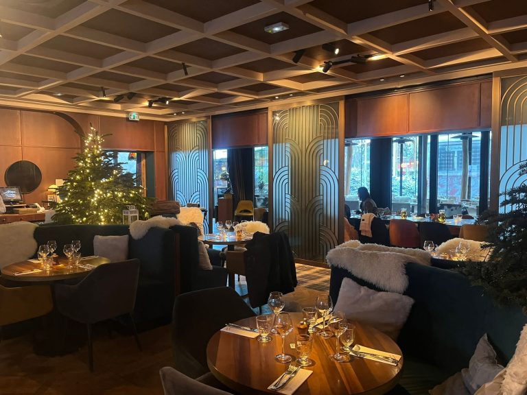 Sapin illuminé et tables dressées dans un restaurant décoré en chalet d’hiver, pour le petit déjeuner de fin d’année de Dior