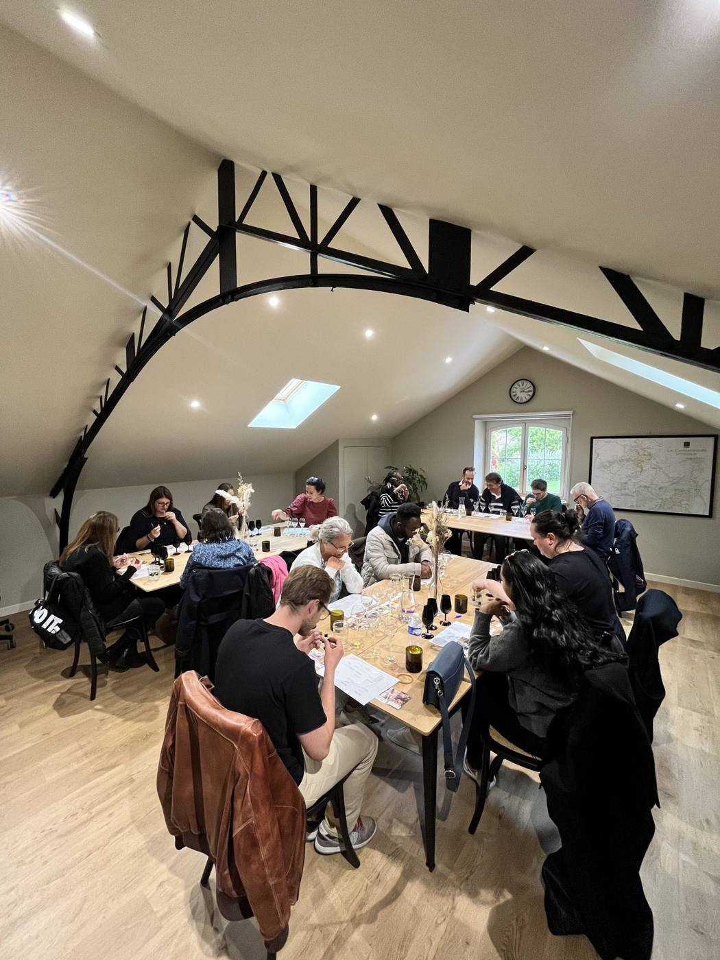 Participants du séminaire Swiss Life attablés pour une dégustation dans une salle mansardée à charpente noire, pendant leur séminaire à Reims organisé par Weevup